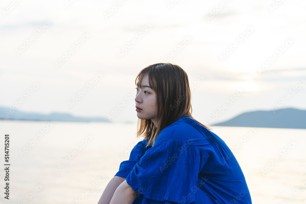 夕暮れの海にいる青いワンピースの女性 夕暮れの海にいる青いワンピースの女性