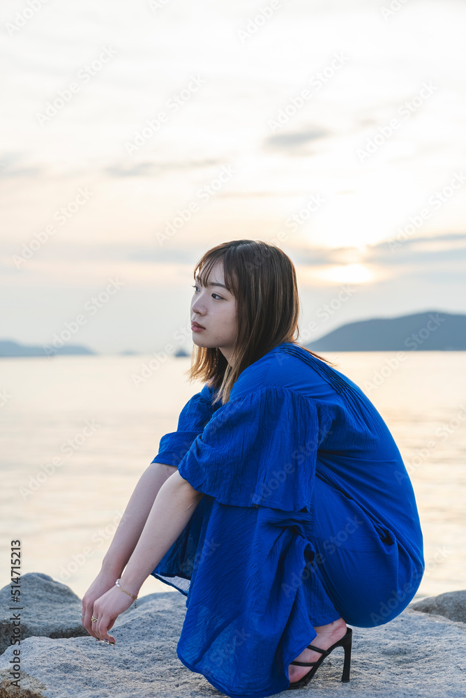 夕暮れの海にいる青いワンピースの女性 夕暮れの海にいる青いワンピースの女性