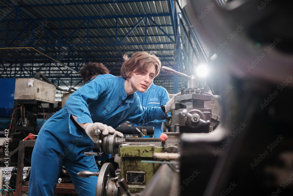 Professional young White female industry engineer worker works in safety uniform with metalwork precision tools, mechanical lathe machines, and spare parts workshop in the steel manufacturing factory. Professional young White female industry engineer worker works in safety uniform with metalwork precision tools, mechanical lathe machines, and spare parts workshop in the steel manufacturing factory.