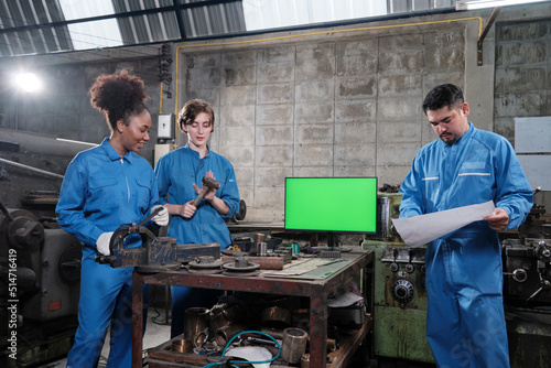 Three multiracial professional industry engineer workers teams in safety uniforms metalwork jobs discuss near green screen monitor, mechanical lathe machines, and workshop in manufacturing factory.