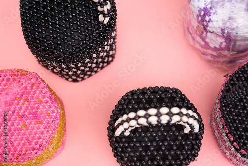 colorful handycrafts from beads on pink background photo