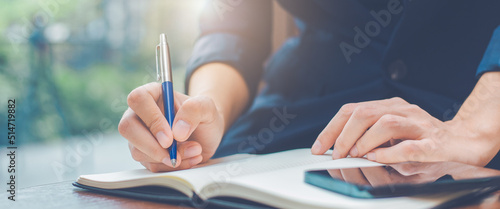 Woman hand writing on a notepad with a pen in the office.