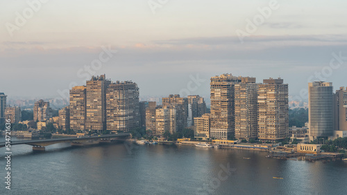 Cairo in the morning. On the embankment  against the pinkish sky - high-rise buildings. The bridge passes over the Nile. Boats are visible on the river. View from the height. Egypt