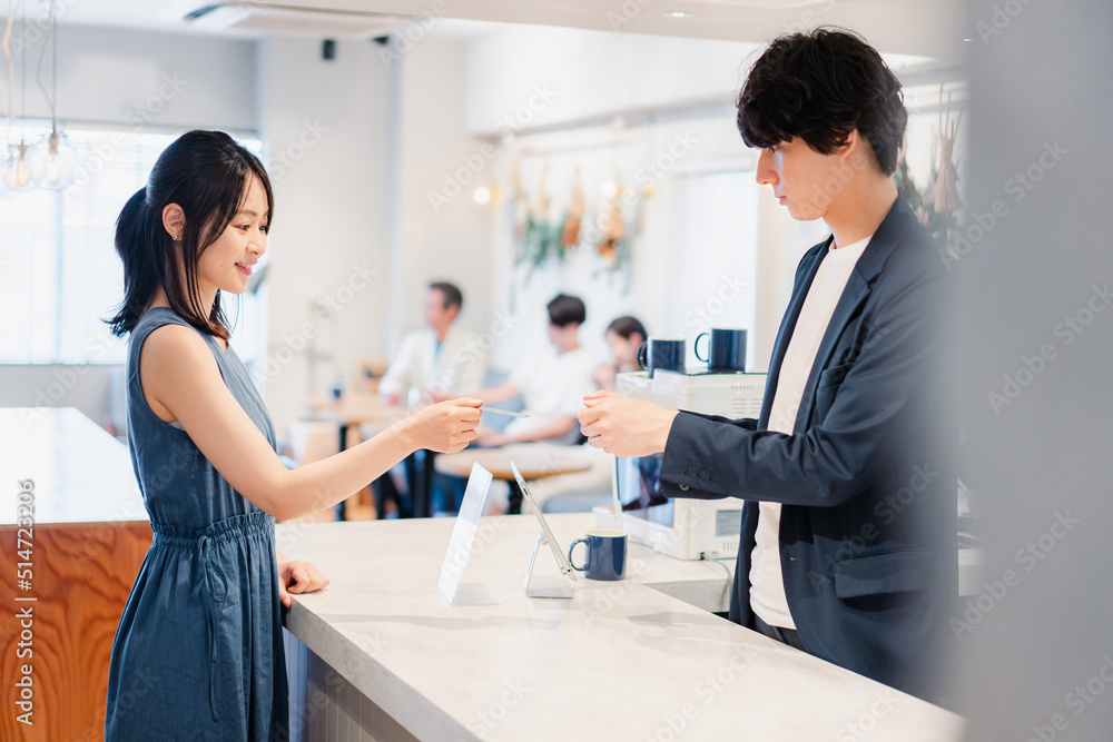 Fototapeta premium レジでクレジットカード決済をする若い女性