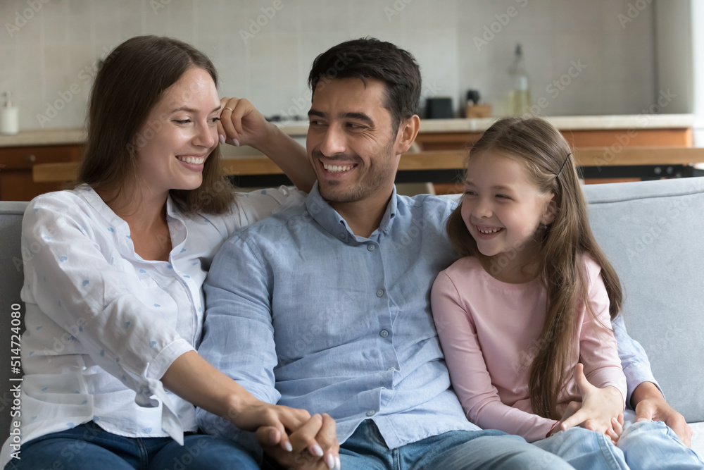 Young couple with cute preschool daughter sit on sofa enjoy pleasant conversation, planning weekend, share dreams, smiling feel happy spend leisure together at home, Communication, family bond concept Young couple with cute preschool daughter sit on sofa enjoy pleasant conversation, planning weekend, share dreams, smiling feel happy spend leisure together at home, Communication, family bond concept
