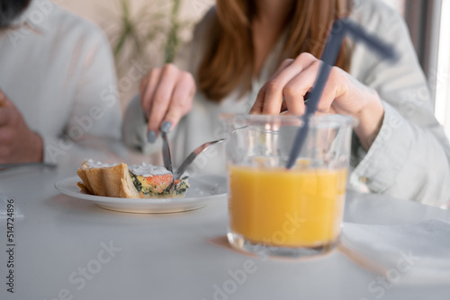 close up of couple having breakfast with fresh juice at home. people and healthy food