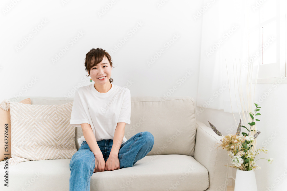 Fototapeta premium 家のソファに座る笑顔の日本人女性（カメラ目線） 