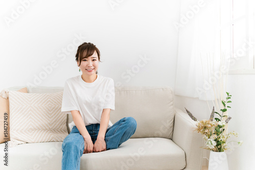 家のソファに座る笑顔の日本人女性（カメラ目線）
