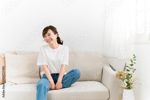 家のソファに座る笑顔の日本人女性（話す） 