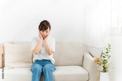 家のソファで思い悩む日本人女性（ショック） 