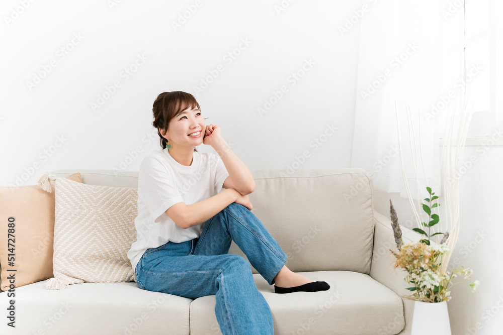 家のソファでリラックスするデニム姿の日本人女性
