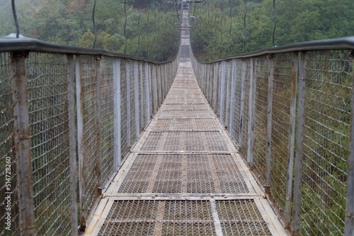 Fog view on the Khndzoresk suspension bridge in the cave city in the mountain rocks. Armenia landscape attraction. Abandoned ruins in the mist. Atmospheric stock photo. photo