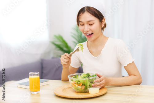 Lifestyle in living room concept, Young Asian woman eating vegetable salad and orange juice