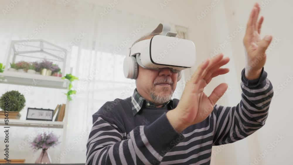 Senior man using VR headset to explore augmented reality at home in living room . Disabled elderly male playing virtual online game, having fun with modern technologies. Senior man using VR headset to explore augmented reality at home in living room . Disabled elderly male playing virtual online game, having fun with modern technologies.