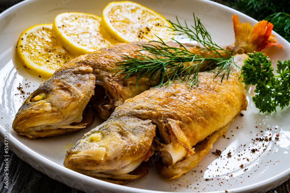 Fried perch with lemon and salad served on wooden table
Fried perch with lemon and salad served on wooden table