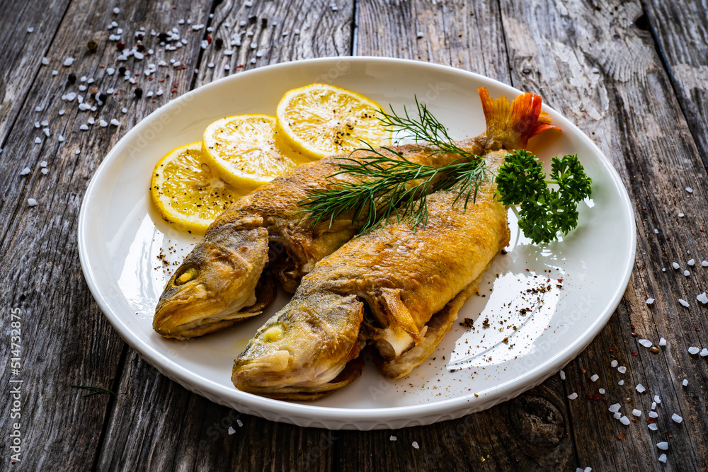 Fried perch with lemon and salad served on wooden table
Fried perch with lemon and salad served on wooden table