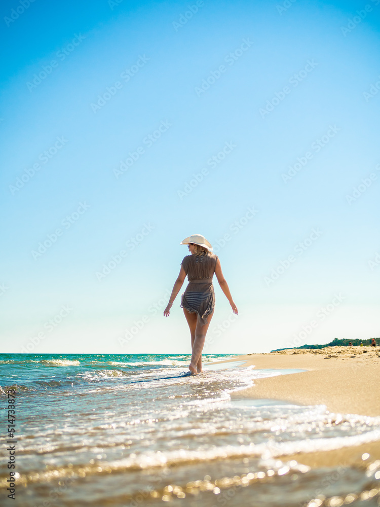 Naklejka premium Woman walking on sunny beach 