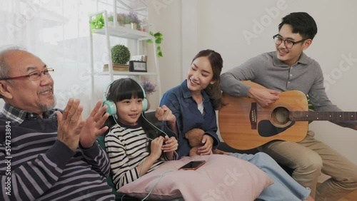 Father mother and daughter  and grand paretn teaching, playing guitar and learning musical notes at home. photo