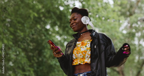 African american woman with smartphone in hand internet communication walking on summer day in park.