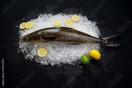 fresh mackerel on ice with lemon on a black background