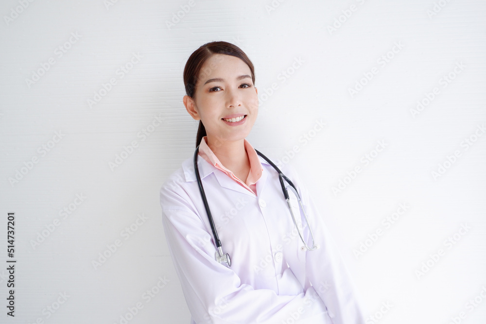 A smiling, beautiful Asian female doctor puts a stethoscope on her shoulder. wearing a white robe on a white background.