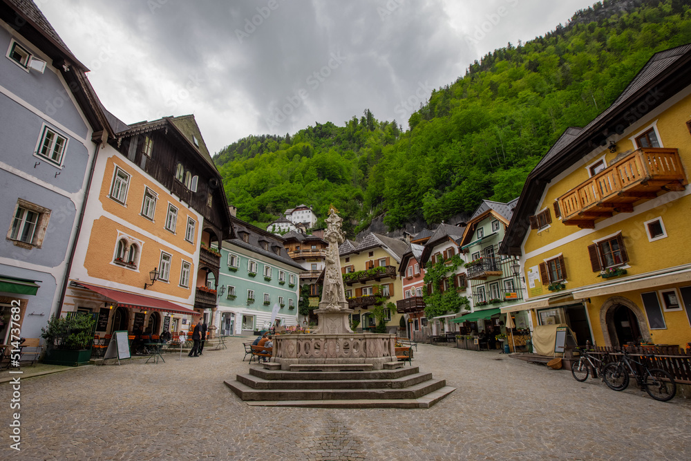 Beautiful town square in Hallstatt, Austria, viewed from a street in the city, with fountain in the foreground. Typical austrian city, famous for its picturesque look.