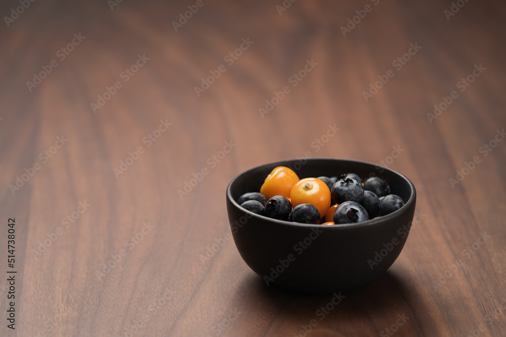 Blueberries with physalis in a bowl on wood table Blueberries with physalis in a bowl on wood table