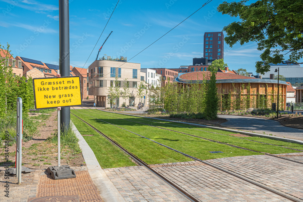 Tracks of the tram or trolley bus on a road with green grass. Electric public transport network in the center city of Odense, Denmark, Europe 