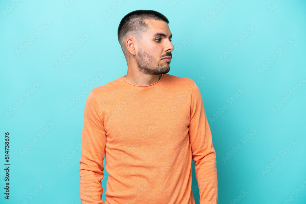 Young caucasian man isolated on blue background looking to the side Young caucasian man isolated on blue background looking to the side