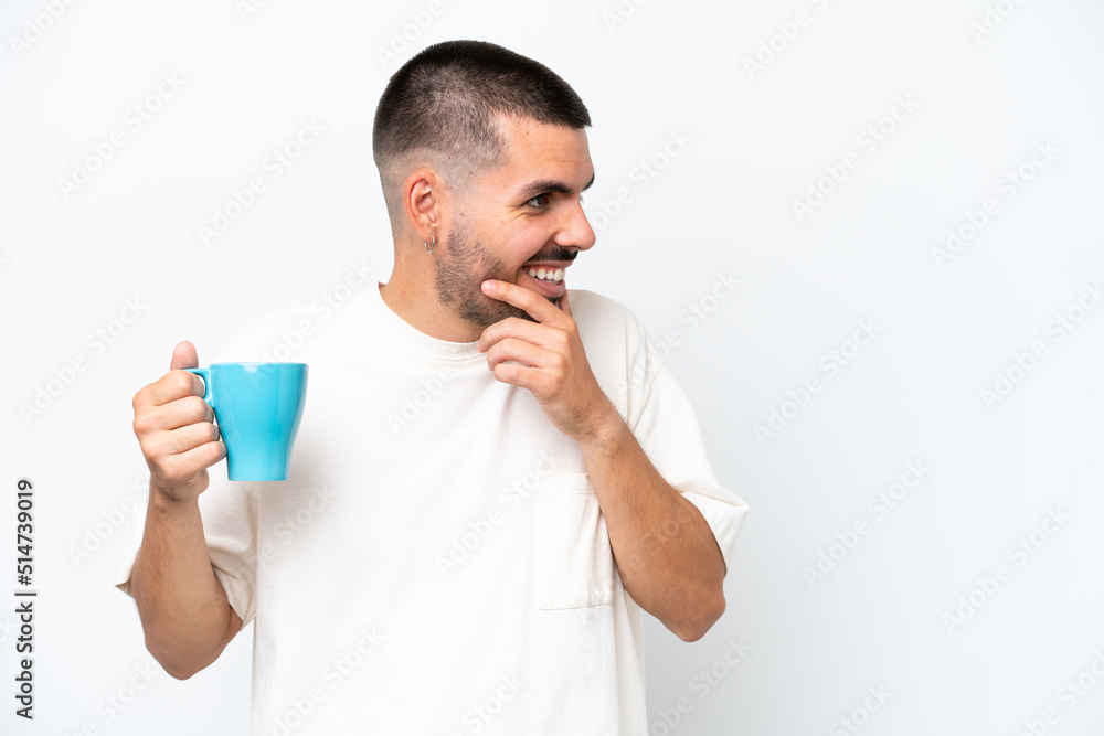 Young caucasian man holding cup of coffee isolated white background thinking an idea and looking side Young caucasian man holding cup of coffee isolated white background thinking an idea and looking side