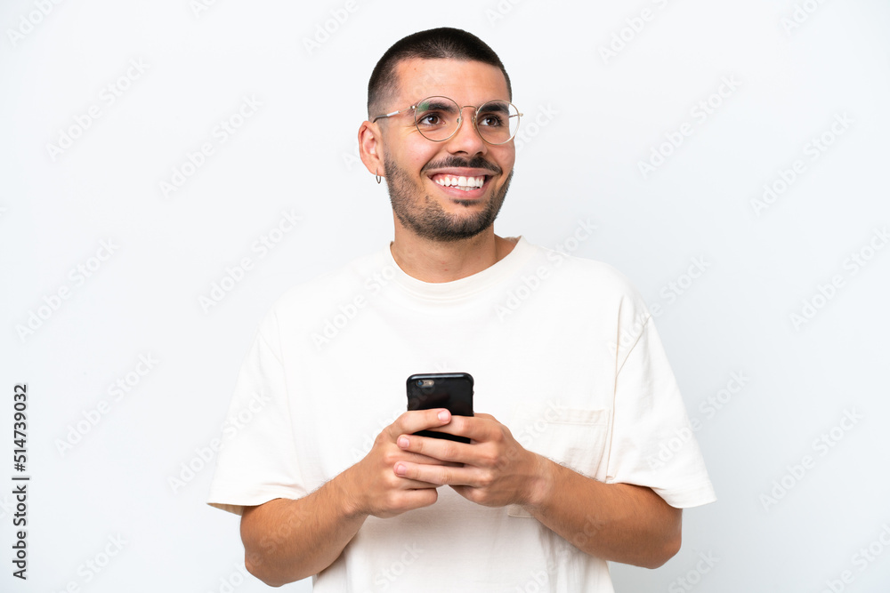 Young caucasian man isolated on white background using mobile phone and looking up Young caucasian man isolated on white background using mobile phone and looking up