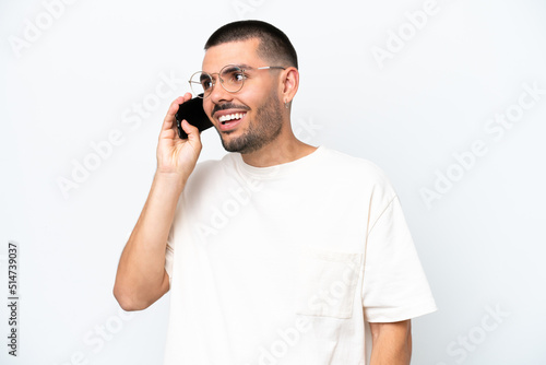 Young caucasian man isolated on white background keeping a conversation with the mobile phone with someone
