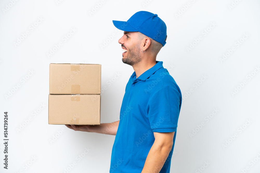 Delivery caucasian man isolated on white background laughing in lateral position Delivery caucasian man isolated on white background laughing in lateral position