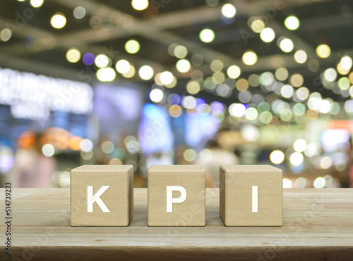 KPI letter on wood block cubes on wooden table over blur light and shadow of shopping mall, Key Performance Indicator business target concept © grapestock