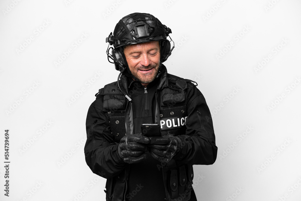 Middle age SWAT man isolated on white background sending a message with the mobile Middle age SWAT man isolated on white background sending a message with the mobile