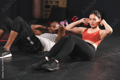 Team mix race man and woman sit up exercise at fitness gym 