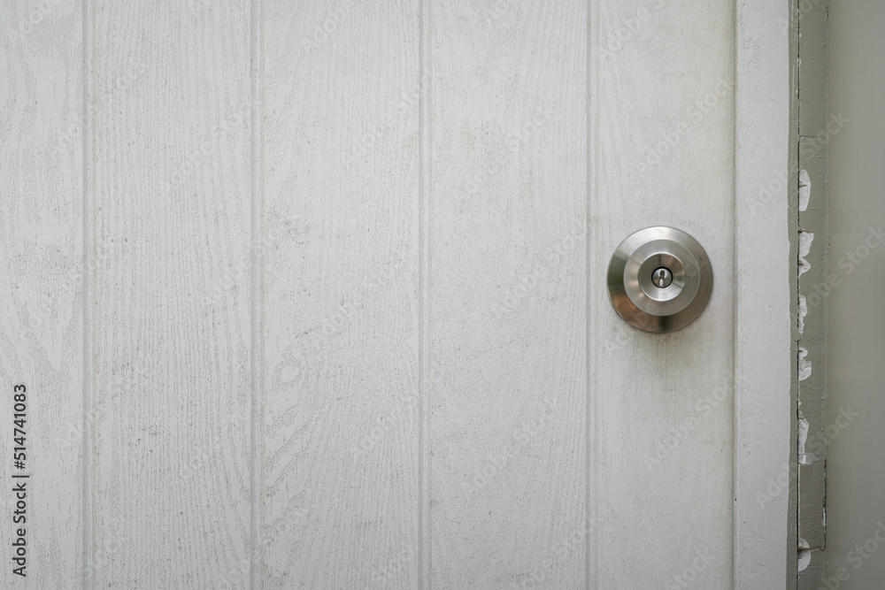 Fototapeta premium Close-up at closed white wooden house door with chrome door's knob. Selective focus.