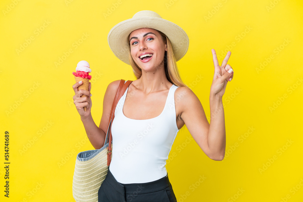 Blonde Uruguayan girl in summertime holding ice cream isolated on yellow background smiling and showing victory sign Blonde Uruguayan girl in summertime holding ice cream isolated on yellow background smiling and showing victory sign