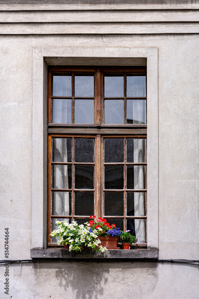 Old wooden window frame with flowers in the town