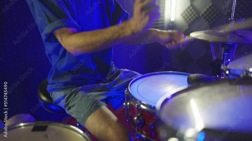 The guy is actively training to play the drums. The camera moves from the drums to the drummer's face The guy is actively training to play the drums. The camera moves from the drums to the drummer's face