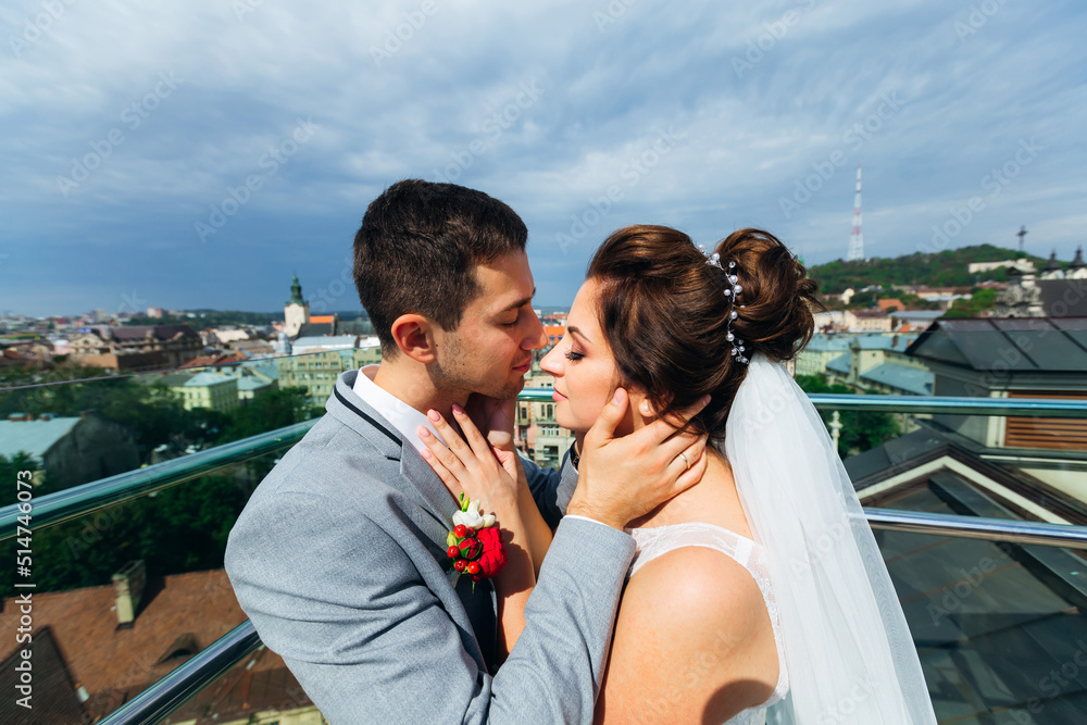 Newlyweds kiss on the balcony with a magnificent view of the cit