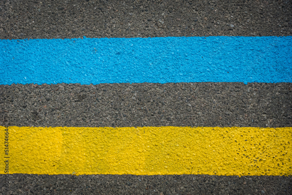 Fototapeta premium Yellow and blue double solid line on the road. Asphalt road with Ukrainian national colors. Flag of Ukraine. War in Ukraine