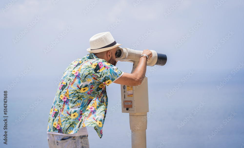 Man watching through binoculars telescope standing on observation point