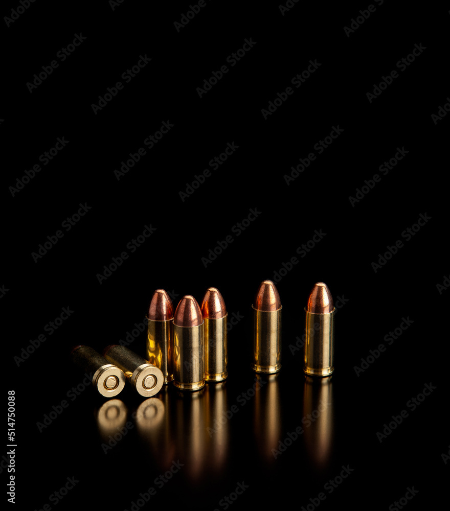 Pistol cartridges 9 mm on a smooth glossy surface with reflections. Ammunition for pistols and PCC carbines on a dark back. Pistol cartridges 9 mm on a smooth glossy surface with reflections. Ammunition for pistols and PCC carbines on a dark back.