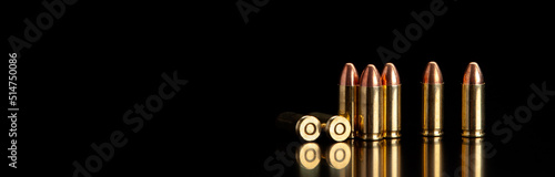 Pistol cartridges 9 mm on a smooth glossy surface with reflections. Ammunition for pistols and PCC carbines on a dark back.