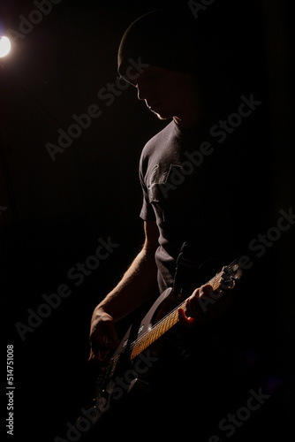 man playing the guitar in the dark with one spotlight © Елена Вырыпаева