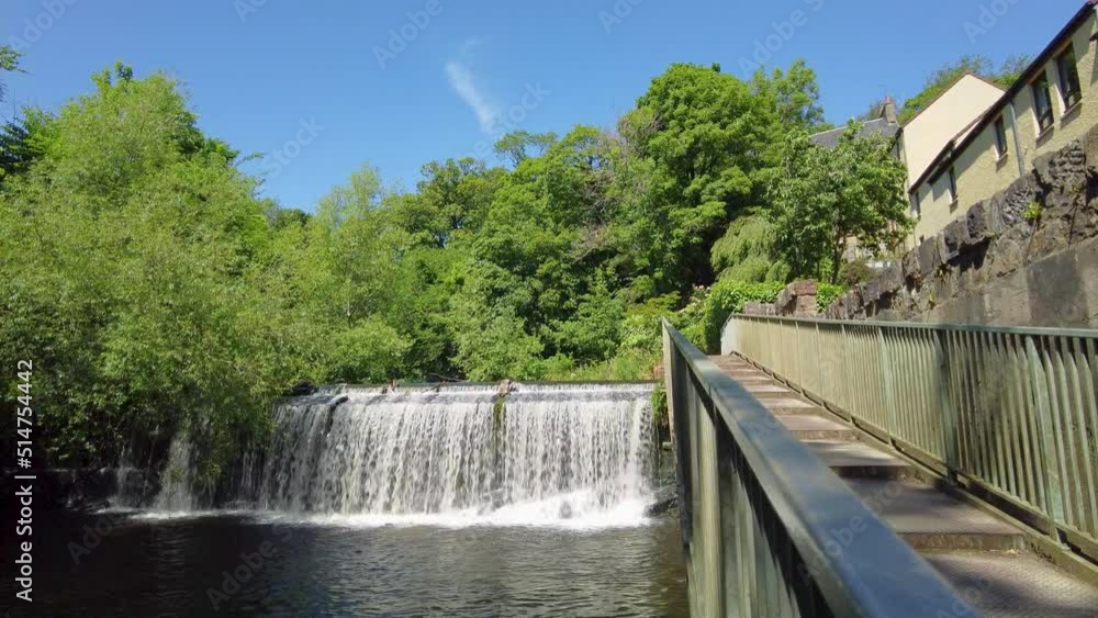 Midlothian, Scotland – June 19 2022. A waterfall on the Water of Leith in the city of Edinburgh captured on a bright and sunny day Midlothian, Scotland – June 19 2022. A waterfall on the Water of Leith in the city of Edinburgh captured on a bright and sunny day