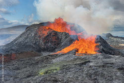Volcano on Iceland's Reykjanes Peninsula. Lava fountains from the volcanic crater. Landscape in spring with sunshine. Liquid lava flows out of the side of the crater. Strong steam rises from crater