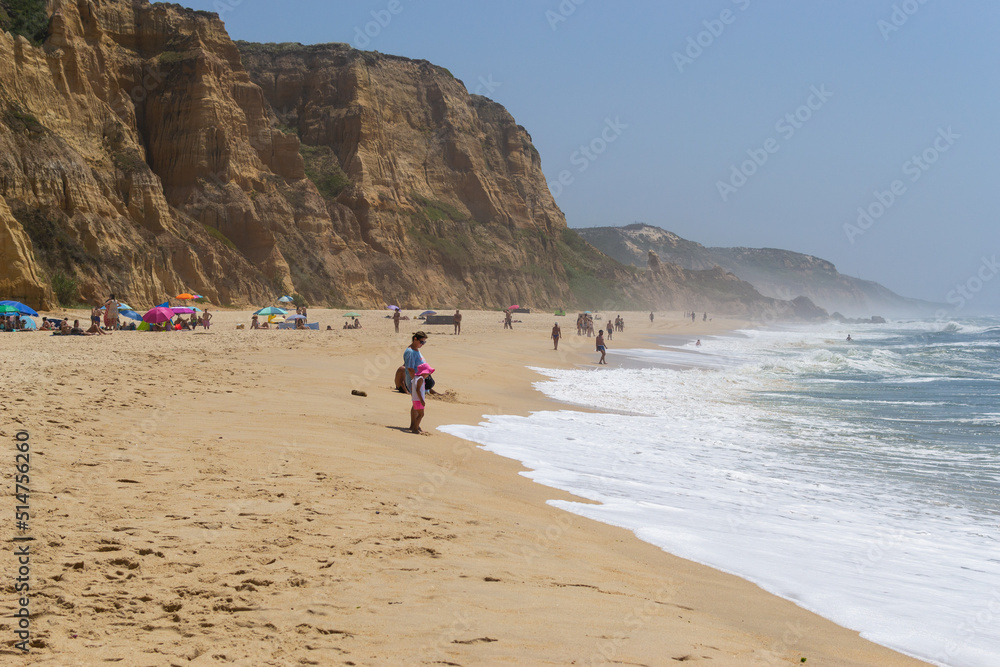 Beach by the ocean with people resting, vacation spot. Mountains, sea and waves. Travel to Europe Portugal. Beach by the ocean with people resting, vacation spot. Mountains, sea and waves. Travel to Europe Portugal.