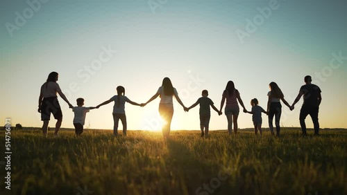 Big happy family. Group of people have fun walking in the park on green grass. Parents and children walk together holding hands at sunset. Family love and support. Family teamwork in park on vacation
